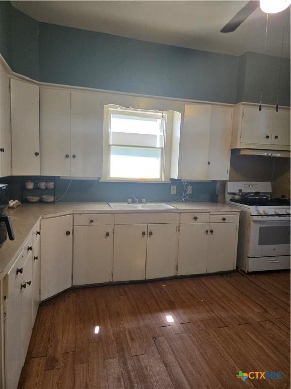 kitchen featuring a sink, dark wood-style floors, white gas stove, and white cabinetry