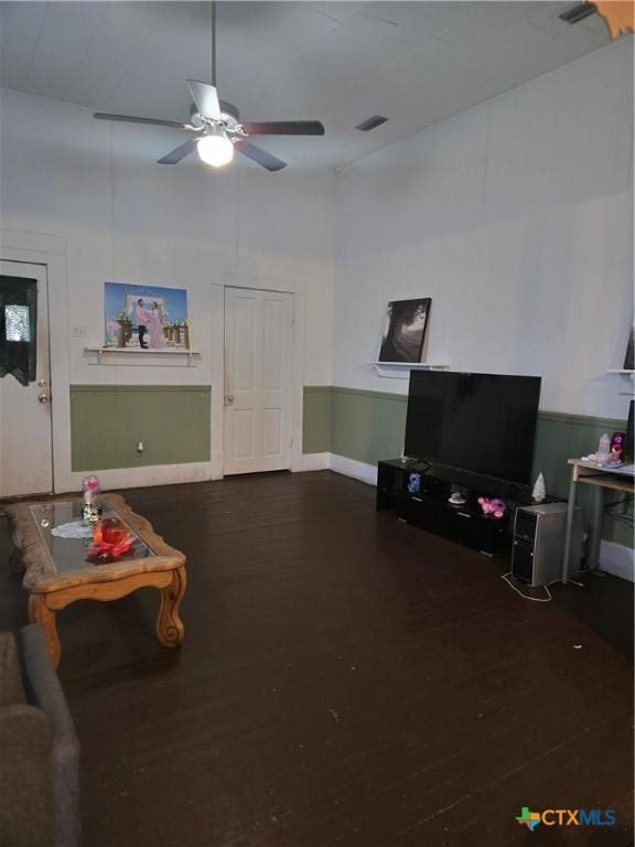 living room with visible vents, dark wood-type flooring, and a ceiling fan