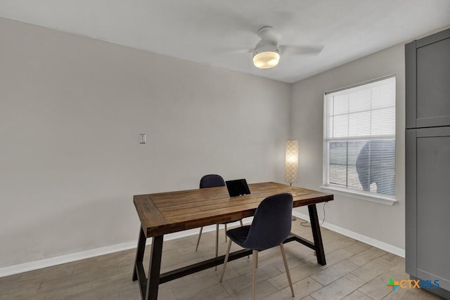 home office featuring a ceiling fan, baseboards, and light wood finished floors