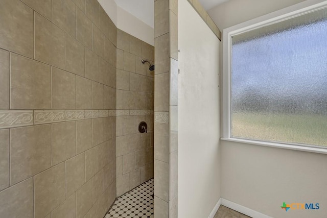 bathroom featuring tiled shower and baseboards