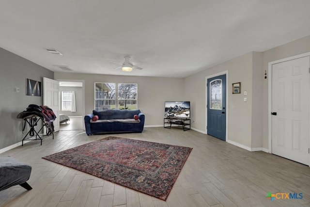 living area featuring a ceiling fan, wood finished floors, visible vents, and baseboards