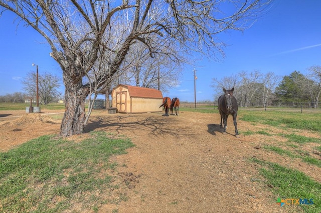 view of yard with a shed, a rural view, fence, and an outbuilding