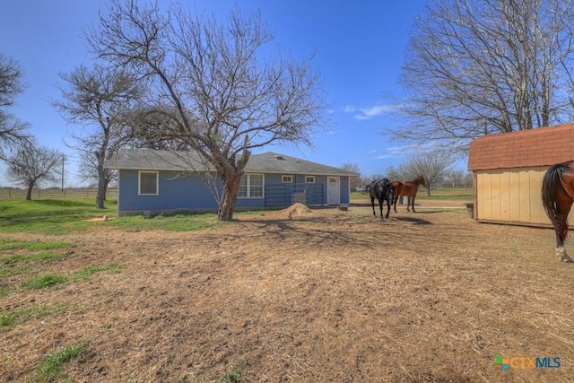 view of yard with a rural view, fence, an outdoor structure, and a shed