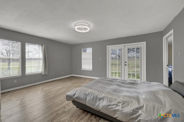 bedroom featuring access to outside, baseboards, wood finished floors, and french doors