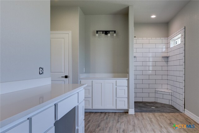 bathroom with hardwood / wood-style flooring and tiled shower