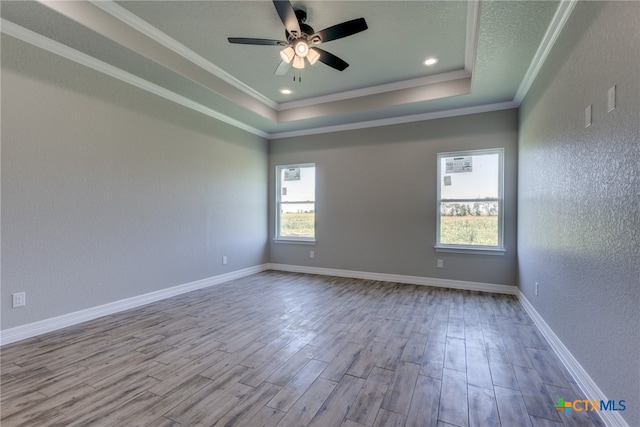 spare room featuring light hardwood / wood-style flooring, ceiling fan, crown molding, and a tray ceiling