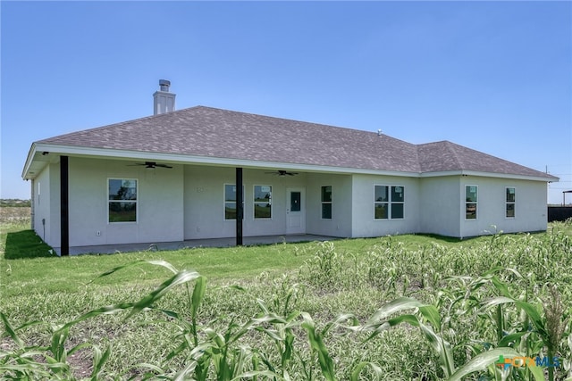 back of property featuring ceiling fan and a lawn