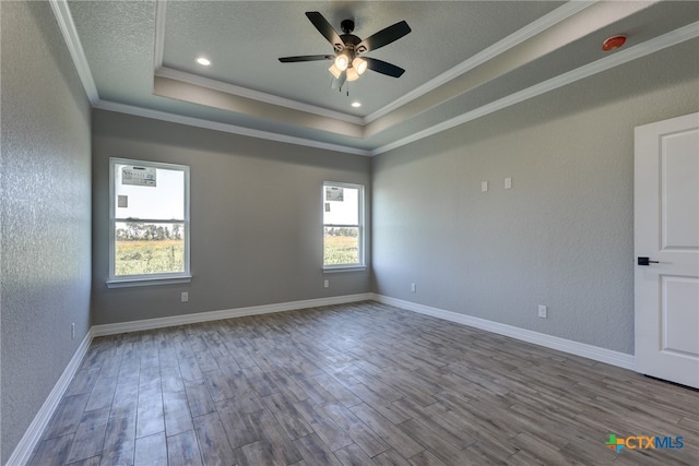 empty room featuring ceiling fan, a wealth of natural light, hardwood / wood-style floors, and ornamental molding