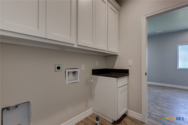 laundry room featuring cabinets, light hardwood / wood-style floors, electric dryer hookup, and hookup for a washing machine