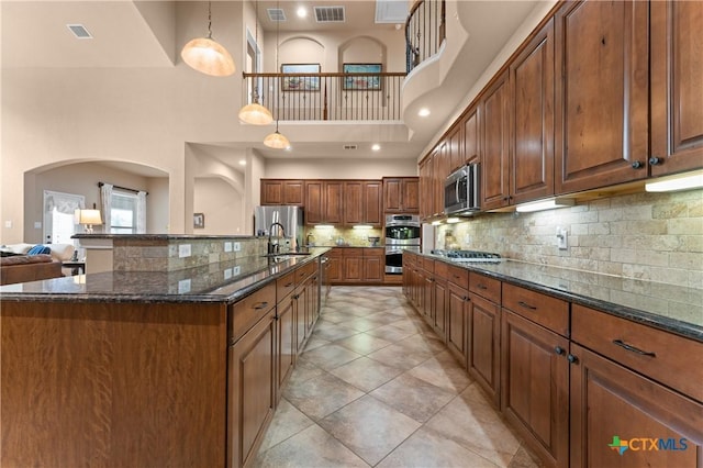 kitchen with a sink, visible vents, stainless steel appliances, and a high ceiling