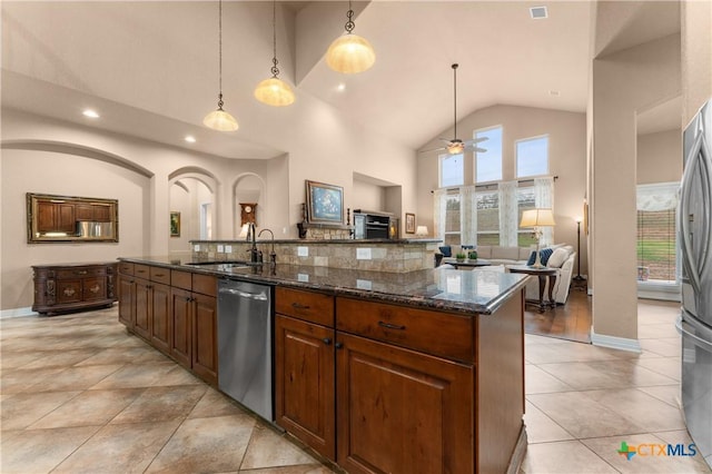 kitchen with a kitchen island with sink, stainless steel appliances, a sink, a ceiling fan, and open floor plan