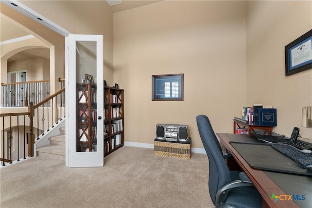 office space featuring baseboards, arched walkways, and carpet floors