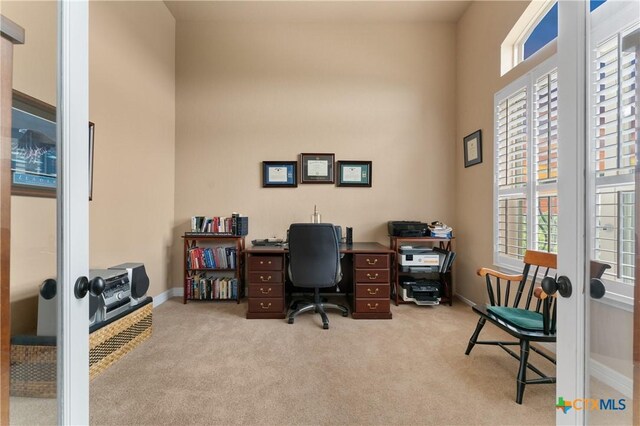 home office with baseboards, french doors, and light colored carpet