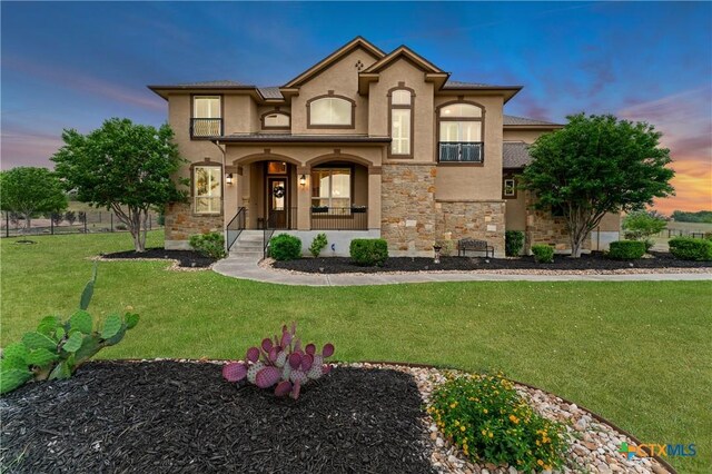 view of front of property featuring stucco siding, a front lawn, and stone siding