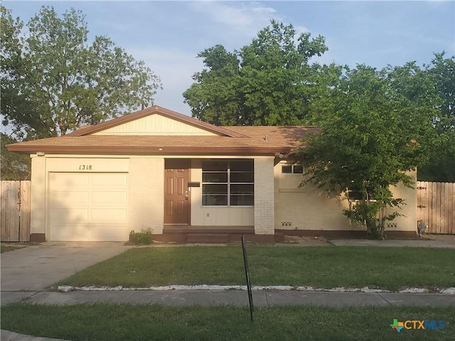single story home with concrete driveway, a front yard, brick siding, a garage, and fence