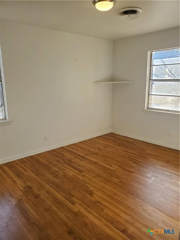 spare room with baseboards and hardwood / wood-style floors