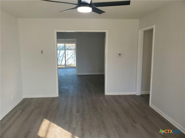 empty room with dark wood-style floors, ceiling fan, and baseboards