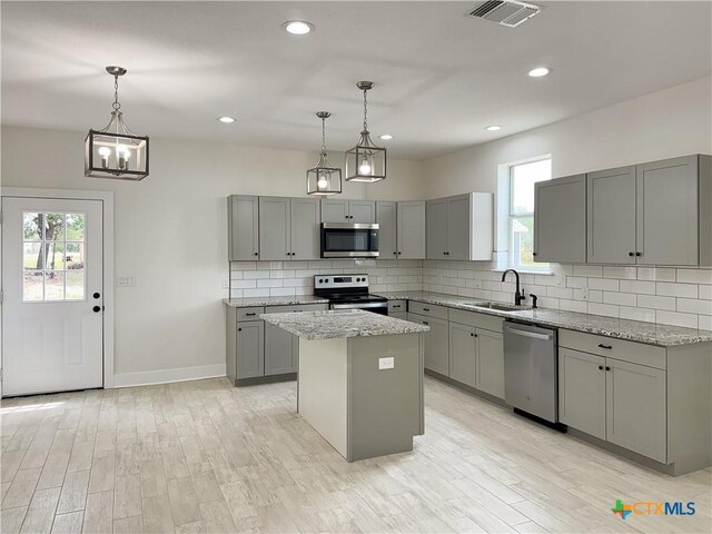 1637 Bob White Dr, Spring Branch, TX 78070 - kitchen featuring stainless steel appliances, gray cabinetry, a sink, a kitchen island, and tasteful backsplash