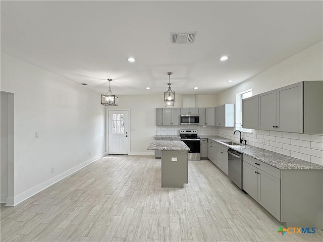 1637 Bob White Dr, Spring Branch, TX 78070 - kitchen with stainless steel appliances, gray cabinets, a sink, a center island, and decorative backsplash