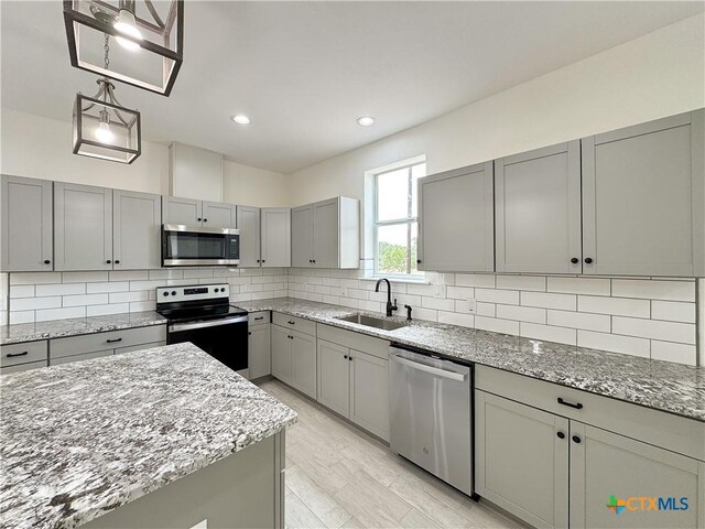 1637 Bob White Dr, Spring Branch, TX 78070 - kitchen with stainless steel appliances, a sink, gray cabinets, light stone counters, and decorative backsplash