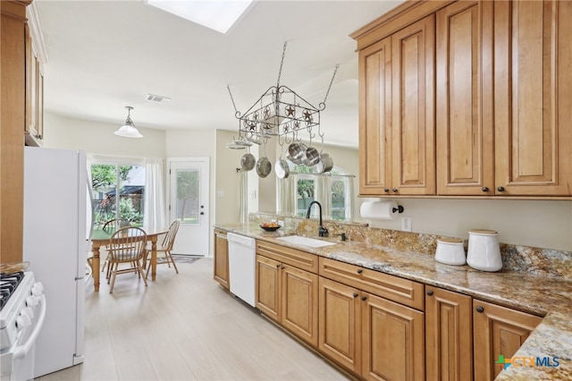 19303 Anna Kate Ct, Pflugerville, TX 78660 - kitchen featuring a sink, white appliances, light stone counters, light wood finished floors, and brown cabinets