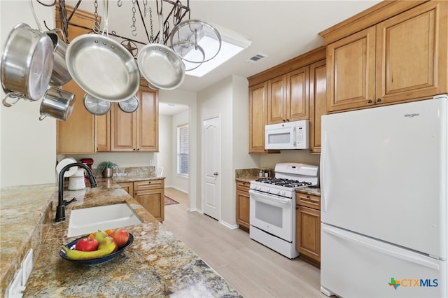 19303 Anna Kate Ct, Pflugerville, TX 78660 - kitchen with white appliances, a sink, light stone counters, light wood-type flooring, and brown cabinetry
