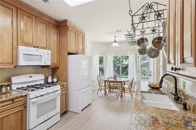 19303 Anna Kate Ct, Pflugerville, TX 78660 - kitchen featuring white appliances, a sink, light wood finished floors, light stone countertops, and brown cabinets