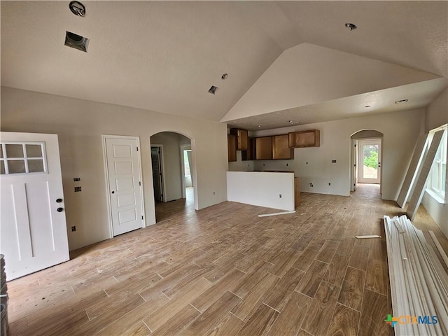 1420 Canyon Bnd, Canyon Lake, TX 78133 - unfurnished living room with arched walkways, light wood finished floors, and high vaulted ceiling
