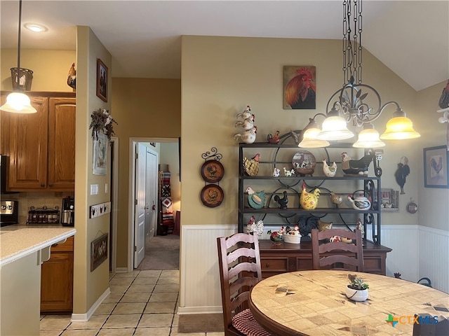 dining space with light tile patterned flooring, vaulted ceiling, and a notable chandelier