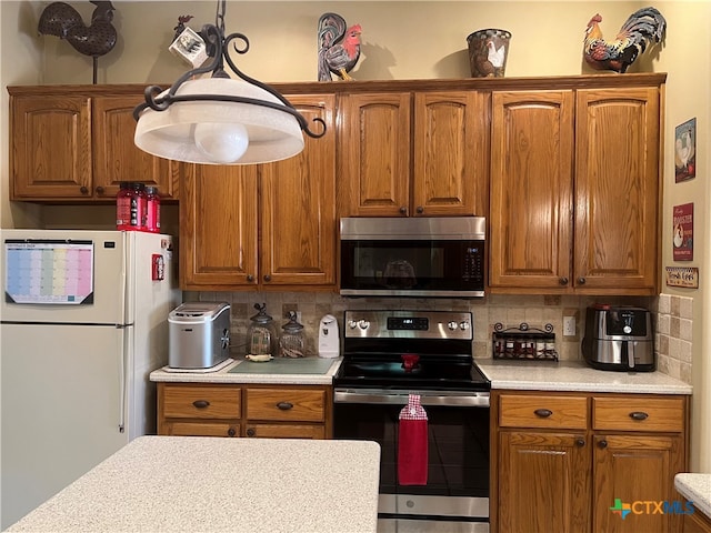 kitchen featuring decorative backsplash, appliances with stainless steel finishes, and hanging light fixtures