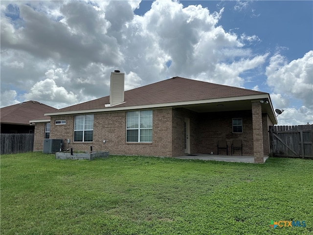 back of house with central air condition unit, a yard, and a patio area