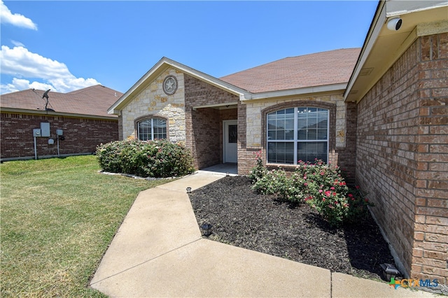 view of exterior entry featuring a lawn