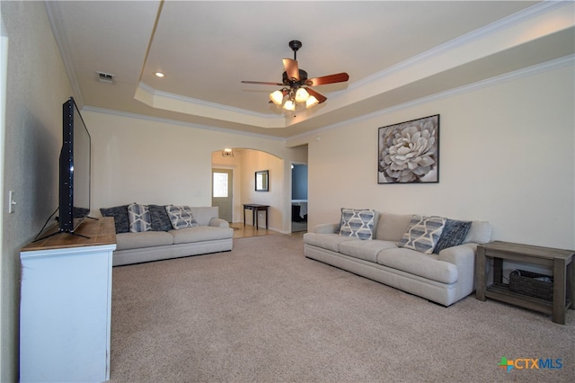 carpeted living room featuring ornamental molding, ceiling fan, and a tray ceiling