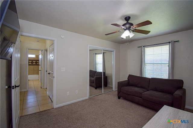 living room with a textured ceiling, light colored carpet, and ceiling fan