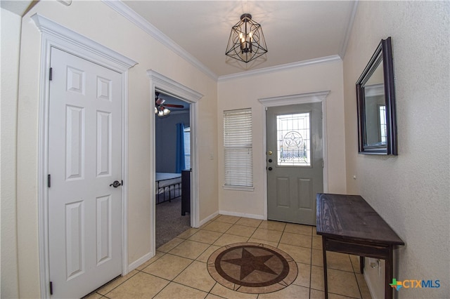 foyer with ceiling fan with notable chandelier, light tile patterned floors, and crown molding