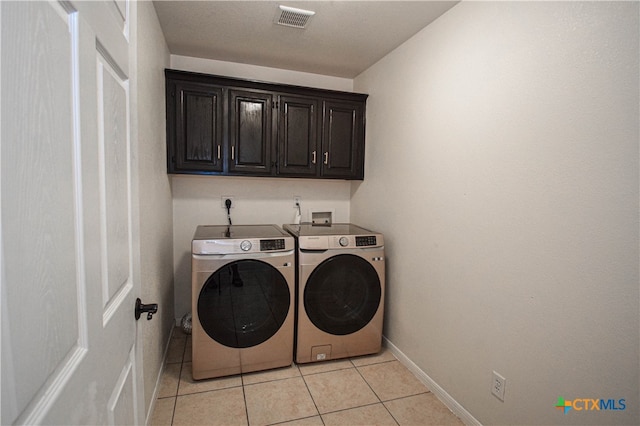 washroom featuring cabinets, light tile patterned flooring, and washer and dryer