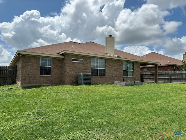 back of house with central AC and a yard