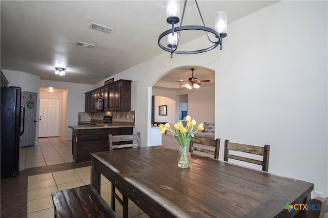 dining room with light tile patterned floors and ceiling fan with notable chandelier