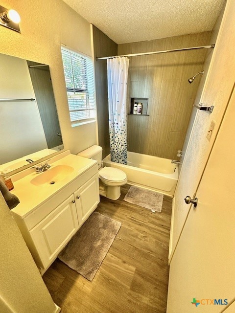 full bathroom with shower / tub combo, a textured ceiling, hardwood / wood-style floors, vanity, and toilet