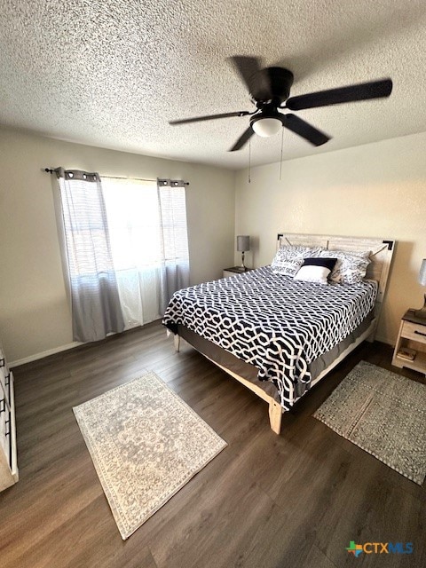 bedroom with ceiling fan, dark hardwood / wood-style floors, and a textured ceiling