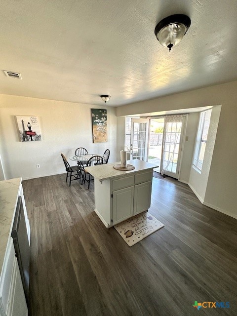 kitchen with dark hardwood / wood-style flooring, white cabinetry, a textured ceiling, and a center island