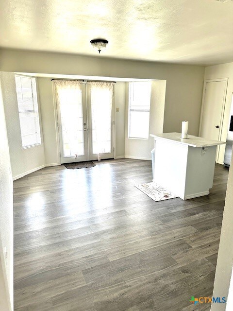 4505 Mustang Dr, Killeen, TX 76549 - unfurnished living room featuring french doors, baseboards, and dark wood-type flooring