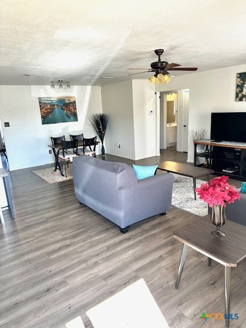 living room with hardwood / wood-style flooring, a textured ceiling, and ceiling fan