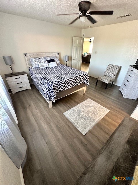 bedroom with a textured ceiling, dark wood-type flooring, and ceiling fan