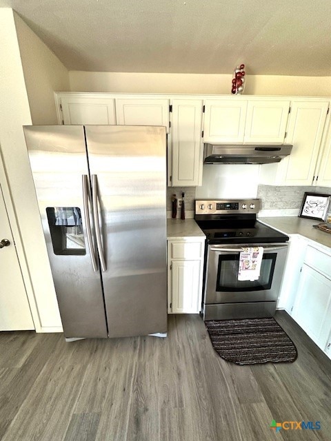 kitchen with appliances with stainless steel finishes, ventilation hood, wood-type flooring, white cabinets, and decorative backsplash