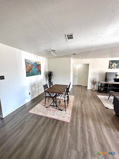 dining room with dark wood-type flooring, ceiling fan, and a textured ceiling