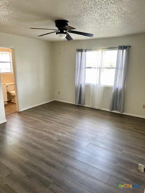 4505 Mustang Dr, Killeen, TX 76549 - spare room featuring dark wood-style flooring, a ceiling fan, a textured ceiling, and baseboards