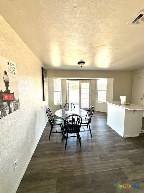 dining room featuring dark hardwood / wood-style flooring and a textured ceiling