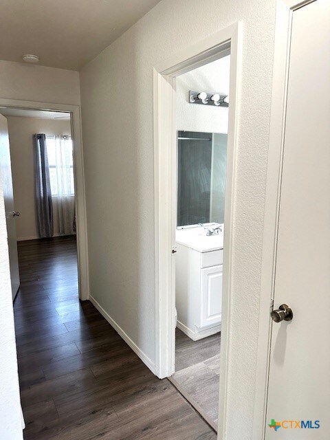 4505 Mustang Dr, Killeen, TX 76549 - hallway with baseboards, dark wood-style floors, and a textured wall