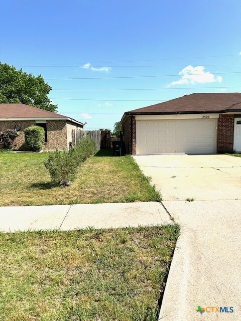 4505 Mustang Dr, Killeen, TX 76549 - view of side of property with brick siding, a yard, an attached garage, and concrete driveway